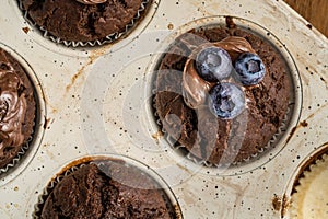 Fresh baked muffins with chocolate cream and blueberries in ceramic pan top view