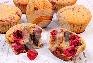 Fresh baked muffins with chocolate and raspberries on wooden background, delicious dessert