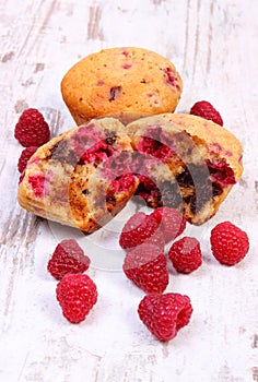 Fresh baked muffins with chocolate and raspberries on wooden background, delicious dessert