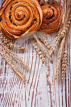 Fresh-baked raisin buns wheat ears on vintage