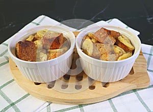 Fresh Baked Two Delectable Banana Bread Pudding in Small Ceramic Bowls on Wooden Breadboard