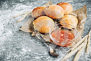 Fresh baked yeast buns filled with apple jam on gray background with flour