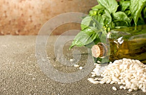 Fresh basil leaves, rice arborio and olive oil on rustic background