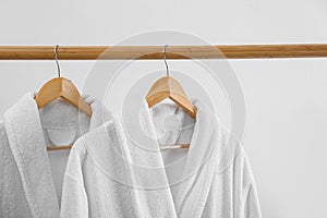 Fresh bathrobes hanging on rack near wall