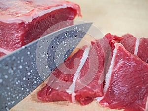 Fresh beef is sliced with sharp ceramic knife.