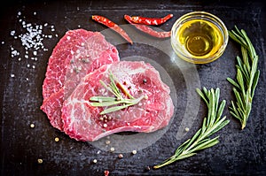 Fresh beef steaks with ingredients on the dark background