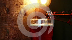 Fresh beer with foam into drink pint glass with ice frozen drops, on gold brown background, fun and nutrition