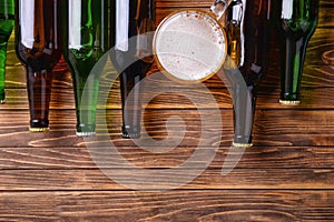 Fresh beer in glass bottles and mug on wooden background