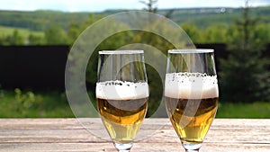 Fresh beer in glasses, outdoors on blurred background.