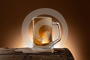 Fresh beer in a mug on a wooden table with spilled foam, a nice dark orange wall as a background in a restaurant photo