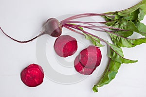 Fresh beetroots with leaves on white table.Whole and cut beetroots