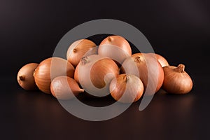 Fresh beige onions on a black background, beautifully photographed, photo for poster, banner.