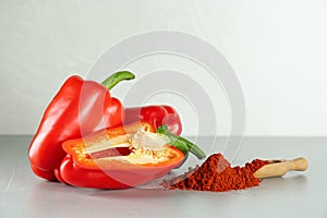 Fresh bell peppers and scoop of paprika powder on white table