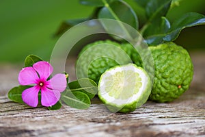 Fresh bergamot fruit and pink flower, Kaffir Lime, Citrus bergamia with leaf on wooden table / Slice bergamot citrus fruit