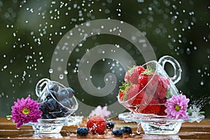 Fresh berries, blueberry and strawberry under the rain with pink flowers