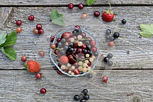 Fresh berries of cherry, gooseberry, currant lie on a glass plate and scattered around it