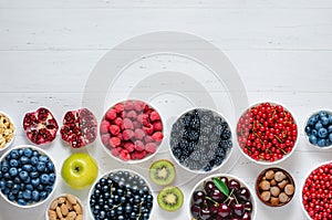 Fresh berries, fruits, nuts on a white wooden background. The concept of healthy eating. Food contains vitamins and