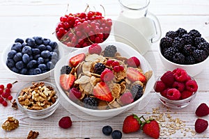 Fresh berries strawberry, raspberries and natural flakes for breakfast, Woman pouring milk into bowl with muesli top