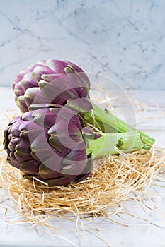 Fresh big Romanesco artichokes green-purple flower heads ready t