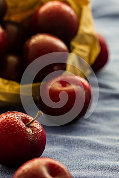 Fresh Black Diamond plums (grown in Portugal) in a brown paper bag on blue cloth background. Selective focus. Back lit.