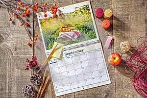 Fresh blank calendar open to September month, sticky note and pe photo