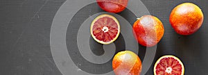 Fresh blood oranges on a black surface, top view. Flat lay, overhead, from above. Copy space