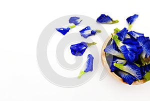 Fresh blue, purple or butterfly pea flowers in brown wooden bowl isolated on white background