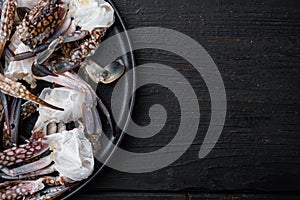 Fresh blue swimming crab Horse crab, Blue crab, Flower crab claws, on plate, on black wooden table background, top view flat lay