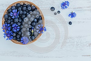 Fresh blueberries in basket with flowers pattern top view. Healthy food on white table mockup. Delicious, sweet, juicy and ripe