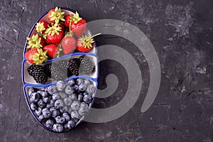 Fresh blueberries, blackberries, strawberries on a separate dish on a gray concrete background. view from above. vegetarian food.