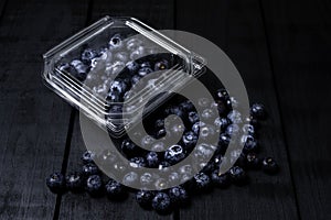 Fresh blueberries inside plastic container on black background