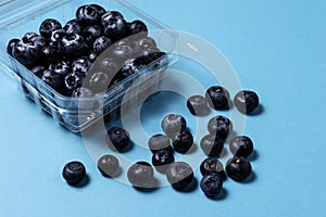 Fresh blueberries inside plastic container on blue background