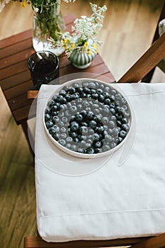 Fresh blueberries on modern ceramic plate, wildflowers bouquet in rustic room. Summer in countryside