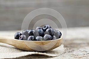 Fresh blueberries in spoon on wooden background