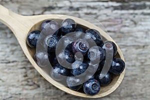 Fresh blueberries in spoon on wooden background