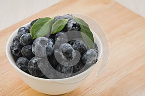 fresh blueberries in white bowl on a wooden background/fresh blueberries in white bowl on a wooden background. selective focus.