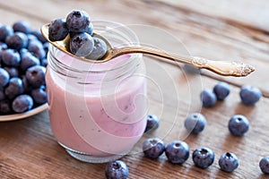 Fresh blueberries yogurt in glass jar, spoon and saucer