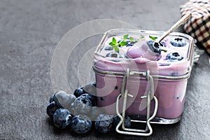 Fresh blueberries yogurt in glass jar on white wooden table