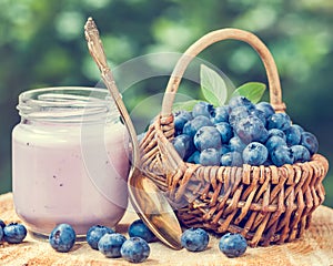 Fresh blueberries yogurt in jar and basket with bilberries.