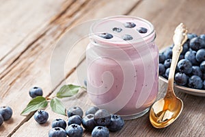 Fresh blueberries yogurt in jar and saucer with bilberries