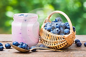 Fresh blueberries yogurt in jar and small basket of bilberries.