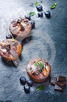 Fresh, blueberry muffins on a stone background with sugar and fruits. Food background. Concept of pastry.