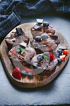 Fresh, blueberry muffins on a stone background with sugar and fruits. Food background. Concept of pastry.