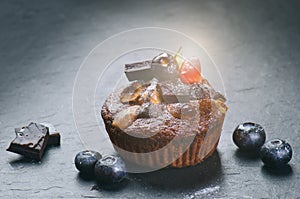 Fresh, blueberry muffins on a stone background with sugar and fruits. Food background. Concept of pastry.