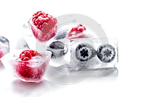 Fresh blueberry and raspberry in ice on table background
