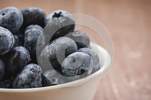 fresh blueberry in a white bowl/ fresh blueberry in a white bowl on a wooden background. Close up