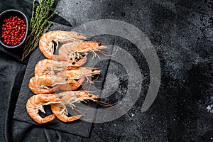 Fresh boiled Prawns, shrimps on a stone Board. Black background. Top view. Copy space