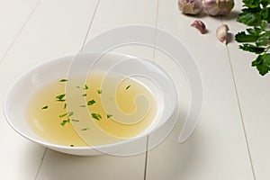 Fresh bouillon in a white plate with finely chopped herbs with parsley and garlic on a white background. photo
