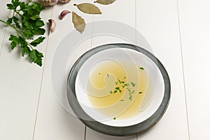 Fresh bouillon in a white plate with finely chopped herbs with parsley and garlic on a white background. photo