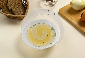 Fresh bouillon in a white plate with herbs and croutons of grain bread. photo